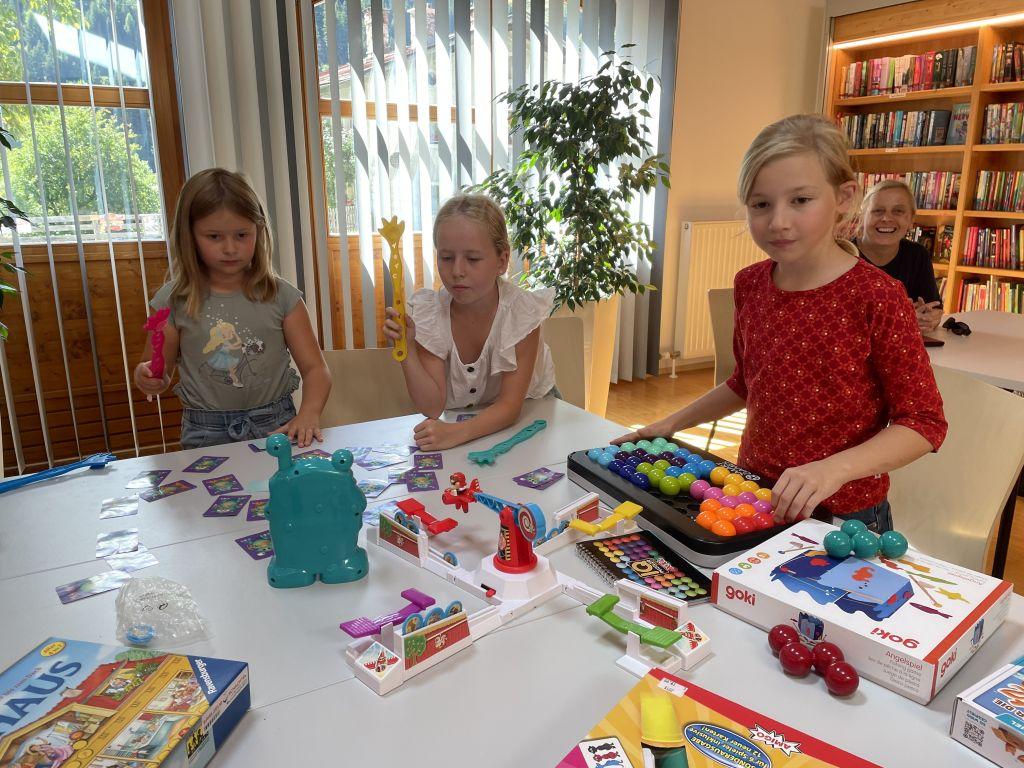 Drei Mädchen mit Spielen am Tisch