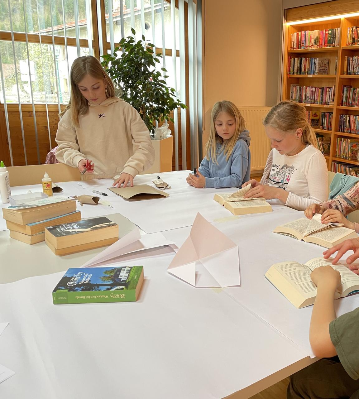 Kinder beim Osterbasteln am Tisch, dahinter Bücherregale
