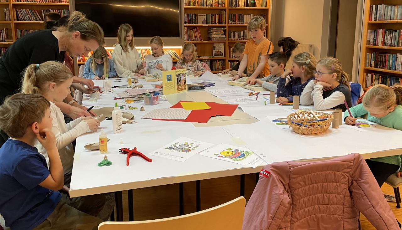 Kinder und eine Erwachsene beim Osterbasteln am Tisch, dahinter Bücherregale