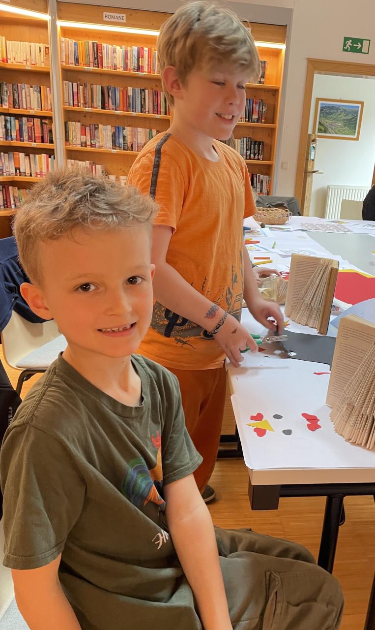 Kinder beim Osterbasteln am Tisch, dahinter Bücherregale