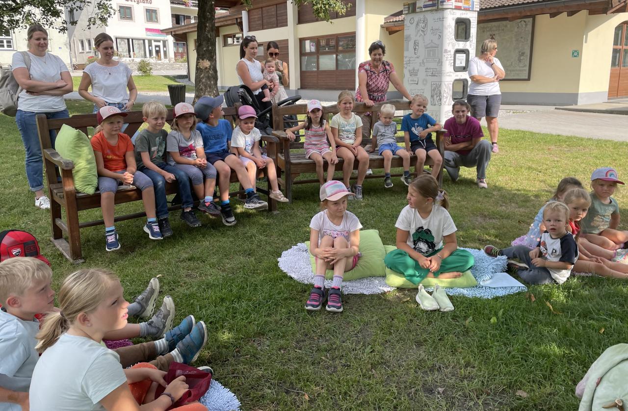 Kinder auf Decken und auf Stühlen sitzend auf der Wiese