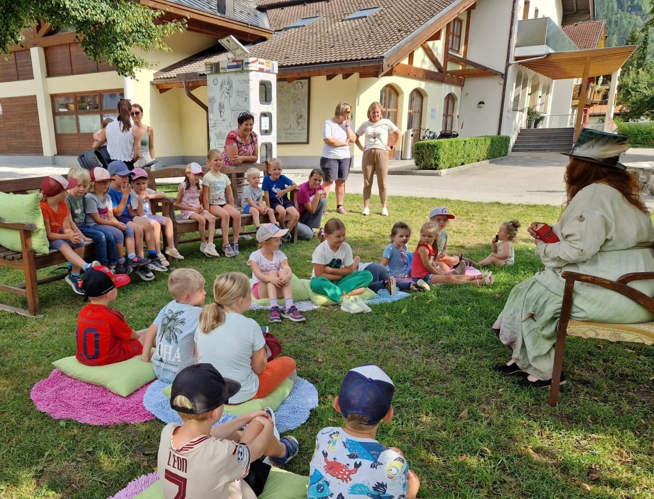 Kinder und Märchenerzählerin auf Decken und auf Sesseln sitzend